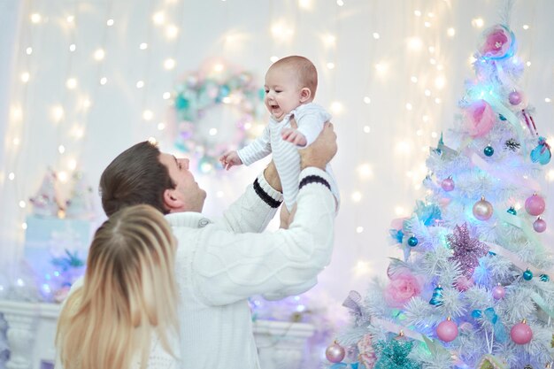 Liebende Eltern spielen an Heiligabend mit ihrem Baby