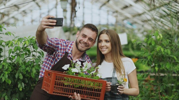 Liebende Gärtnerpaare, die während der Arbeit im Gewächshaus ein Selfie-Foto mit der Smartphone-Kamera machen