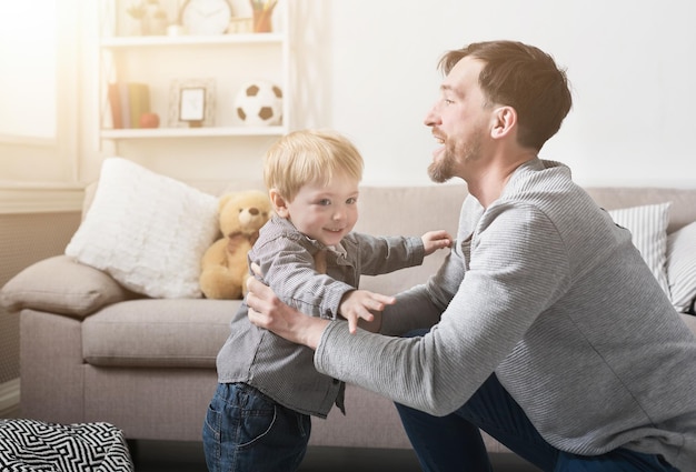 Liebender Vater, der zu Hause im Wohnzimmer mit dem kleinen Jungen spielt und Zeit verbringt