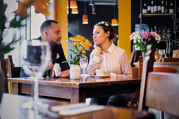 Liebendes schwarzes amerikanisches Paar bei einem Date, das Wein in einem Restaurant trinkt.