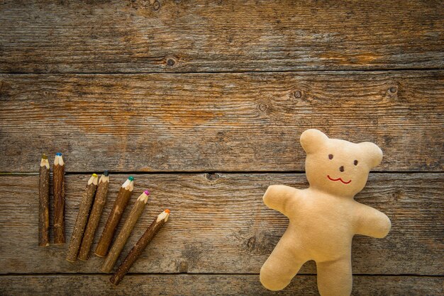 Liebenswerter Teddybär und farbige Bleistifte auf einem Holztisch Platz für Text