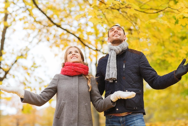 Liebes-, Beziehungs-, Familien-, Saison- und Personenkonzept - lächelndes Paar, das im Herbstpark nach oben schaut