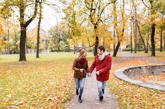 Liebes-, Beziehungs-, Jahreszeiten- und Menschenkonzept - glückliches junges Paar, das im Herbstpark läuft und sich unterhält