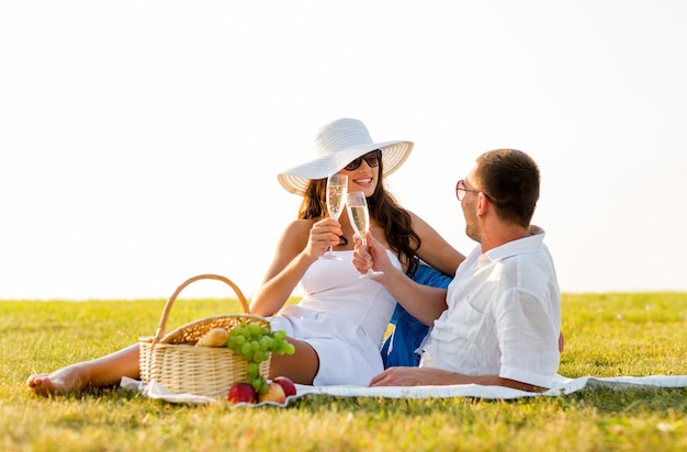 Liebes-, Dating-, Menschen- und Urlaubskonzept - lächelndes Paar, das beim Picknick Champagner trinkt