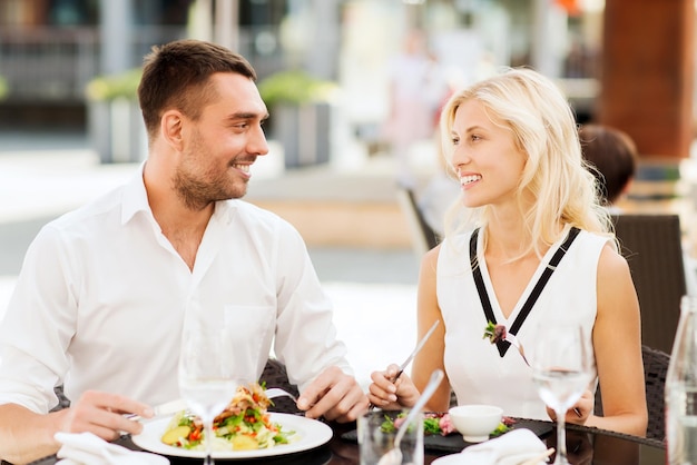 Liebes-, Datums-, Menschen-, Feiertags- und Beziehungskonzept - glückliches Paar, das Salat zum Abendessen im Café oder auf der Restaurantterrasse isst