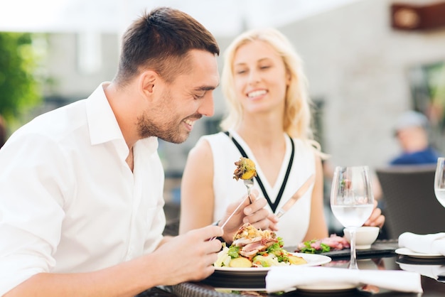 Liebes-, Datums-, Menschen-, Feiertags- und Beziehungskonzept - glückliches Paar, das Salat zum Abendessen im Café oder auf der Restaurantterrasse isst