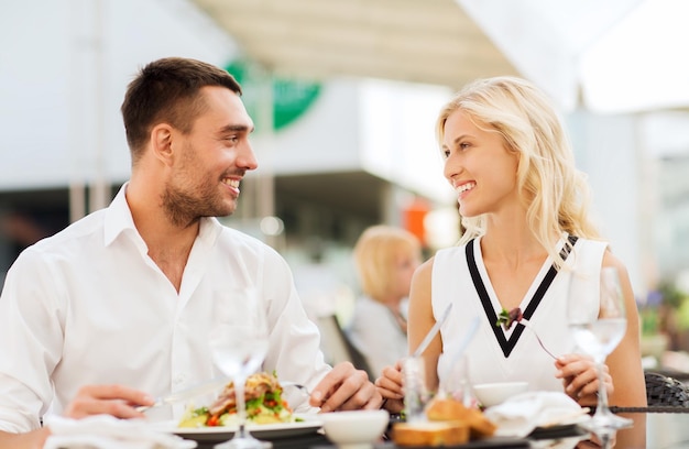 Liebes-, Datums-, Menschen-, Feiertags- und Beziehungskonzept - glückliches Paar, das Salat zum Abendessen im Café oder auf der Restaurantterrasse isst