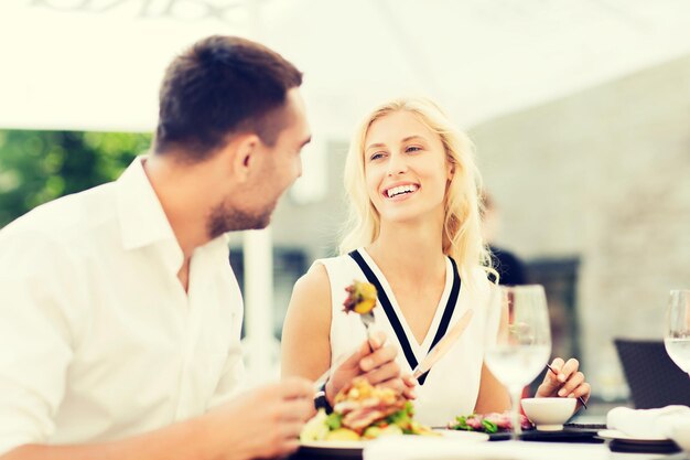 Liebes-, Datums-, Menschen-, Feiertags- und Beziehungskonzept - glückliches Paar, das Salat zum Abendessen im Café oder auf der Restaurantterrasse isst