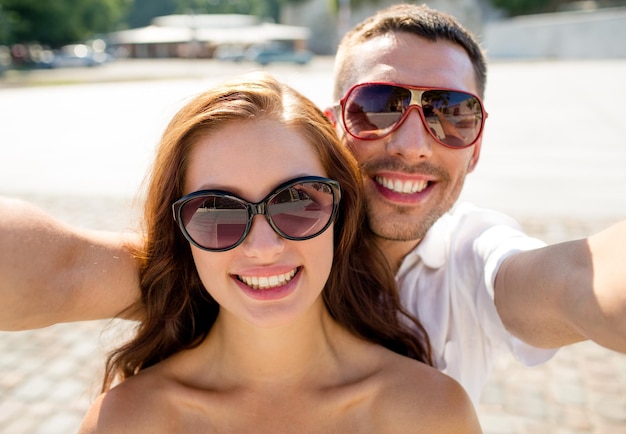 Liebes-, Hochzeits-, Sommer-, Dating- und People-Konzept - lächelndes Paar mit Sonnenbrille, das Selfie in der Stadt macht