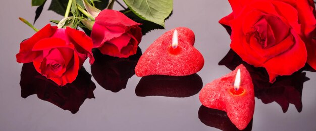 Liebes- und Valentinstagskonzept aus roter Rose und Kerzen auf schwarzem Hintergrund. Draufsicht mit Kopierbereich, flach liegend.