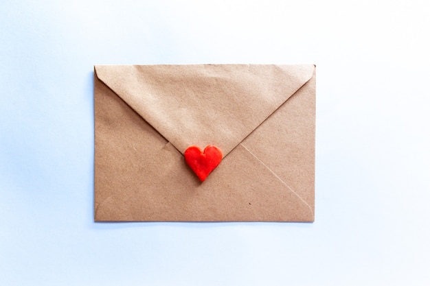 Liebesbrief in einem Handwerksumschlag mit rotem Tonherz auf hellblauem Hintergrund.