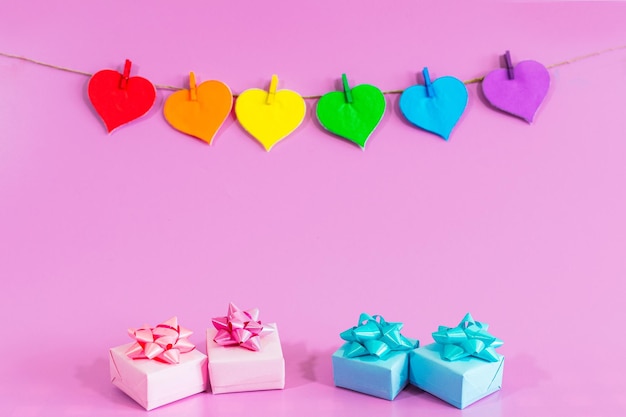 Liebesherzen mit den Farben von LGBT und rosa blauen Geschenken auf rosa Hintergrund