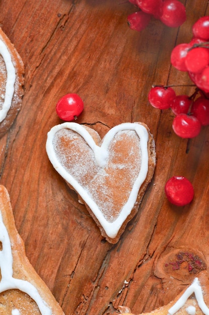 Liebeskonzept mit roten Beeren und Keksen in Form von Herzen Reife rote Beeren und Kuchen auf Holzhintergrund