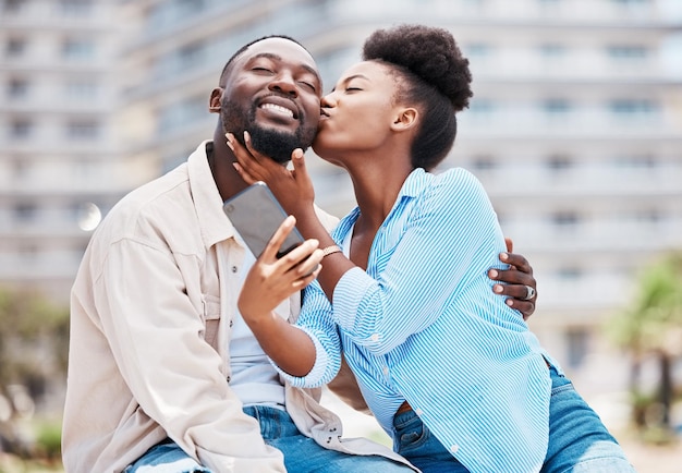 Liebeskuss und Paar machen Telefon-Selfie bei romantischem Date zusammen glücklich und lächeln, während sie sich im Sommerurlaub im Freien entspannen Schwarze Frau und Mann auf einem romantischen Reiseabenteuer oder einer Reise in der Großstadt