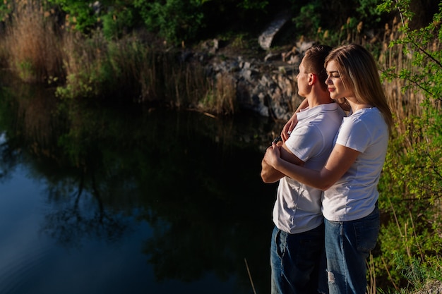 Liebespaar an einem felsigen Ufer. Glückliche Frau und Mann genießen schönen See Mann und eine Frau, die ein Wochenende in der Natur genießen. Junge Paare in der Liebe, die miteinander schaut und Hand zusammenhält