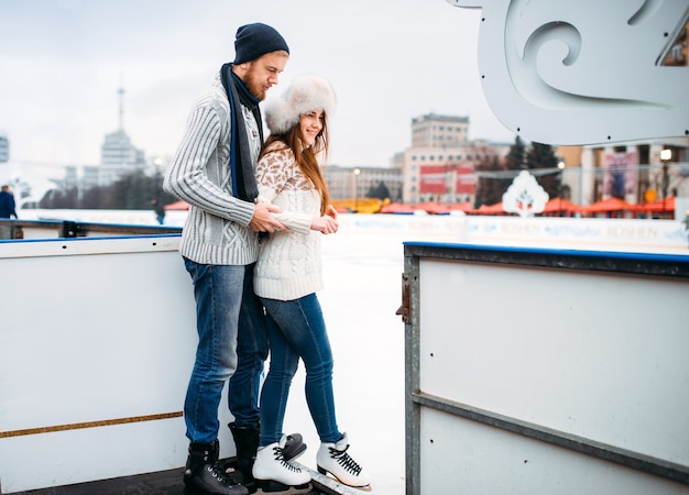 Liebespaar bereitet sich auf die Eisbahn vor. Winterlauf unter freiem Himmel, aktive Freizeit, Eislaufen