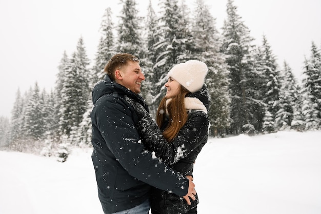 Liebespaar, das auf einem Winterspaziergang kuschelt. Junge Familie, die Spaß im frostigen Wald hat. Romantisches Date im Winter. Winter-Liebesgeschichte