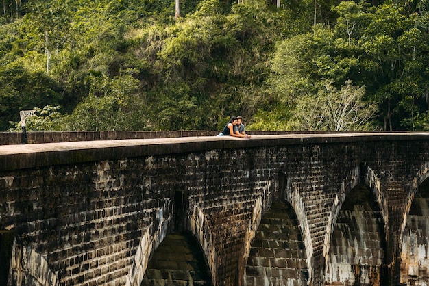 Liebespaar, das sich auf der Brücke umarmt. Kerl und Mädchen reisen durch Asien. Das Paar reist nach Sri Lanka. Mann und Frau an einem ungewöhnlichen Ort. Neun-Bögen-Brücke. Reisende in Asien. Flitterwochen
