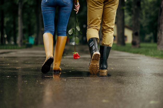 Liebespaar geht im Park, regnerischer Sommertag. Mann und Frau entspannen sich zusammen, romantisches Date auf dem Gehweg, nasses Wetter in der Gasse