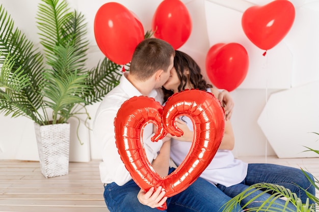 Liebespaar gratuliert einander zum Valentinstag, umarmt und küsst sich und hält ein großes rotes Herz