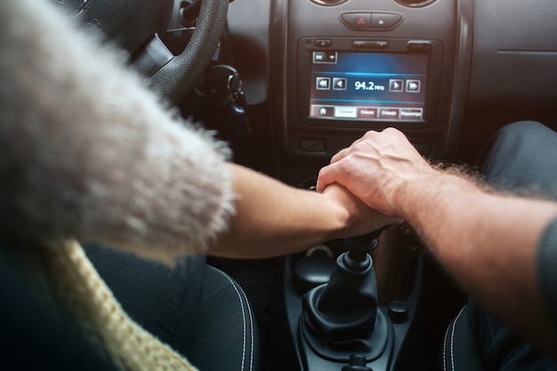 Liebespaar Hand in Hand im Auto. Herbst. Herbstliche Waldreise mit dem Auto.