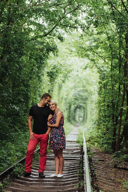 Liebespaar in einem Tunnel der grünen Bäume auf der Eisenbahn