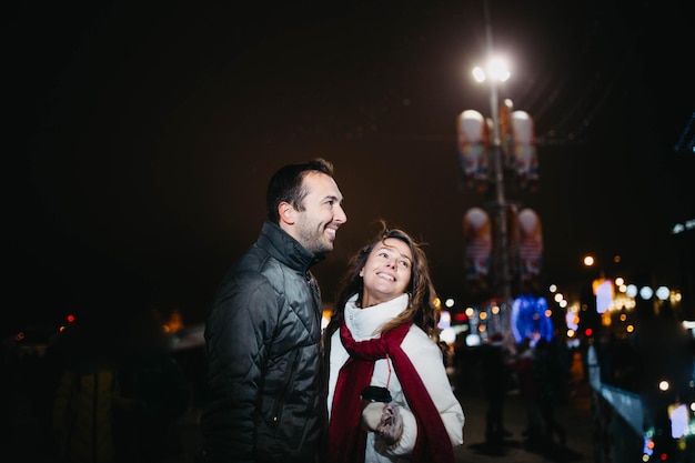 Liebespaar in einer festlichen Stadt mit Neujahrslichtern am Winterabend. Ehepartner im Wintergerinnsel