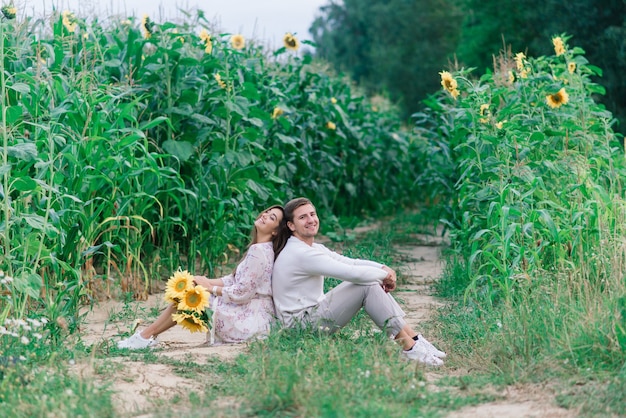 Liebespaar in weißen Kleidern, die in einem Feld von Sonnenblumen aufwerfen