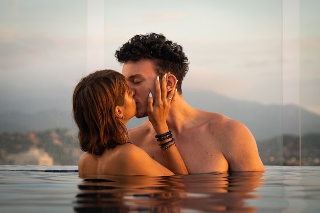 Foto liebespaar küsst sich im infinity-pol-wasser während des romantischen urlaubskonzepts des sonnenuntergangs