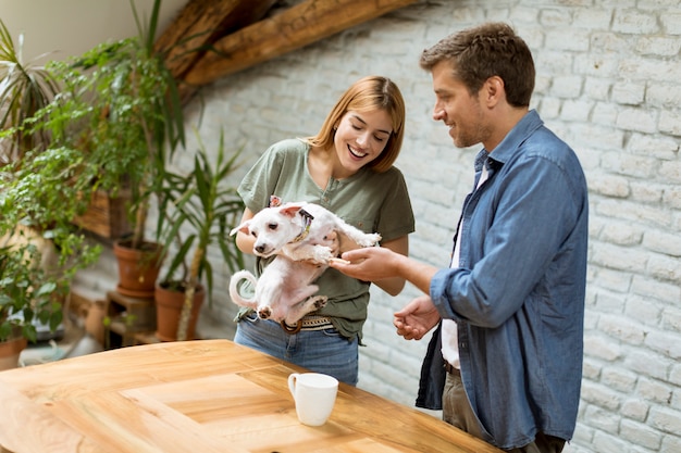 Liebespaar mit niedlichen weißen Hund im Raum