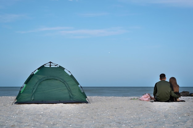 Liebespaar sitzt in der Nähe von Zelt am Meer Camping am Strand