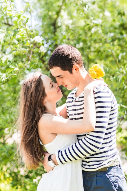 Liebespaar unter blühenden Zweigen Frühlingstag. Junger erwachsener brünetter Mann und Frau, die im frischen Blütenapfel- oder Kirschbaumgarten küssen. süßer Kuss