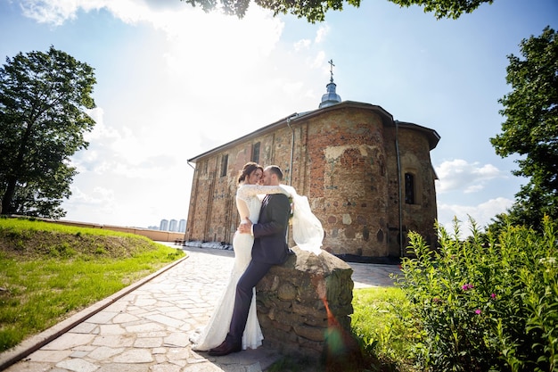 Foto liebespaar von jungvermählten geht an sonnigen sommertagen in der nähe der alten kirche spazieren