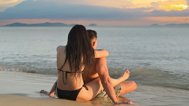 Liebespaare reisen zusammen am Sonnenuntergangsstrand. Zweisamkeit und Lifestyle im Sommerurlaub.