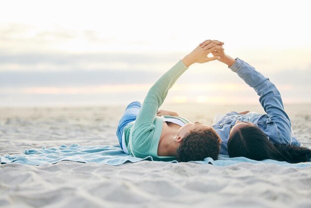 Liebesstrand und lesbisches Paar auf einer Decke, Händchen haltend im Sand und Sonnenuntergangsurlaubsabenteuer. LGBT-Frauen verbinden sich und entspannen sich im Urlaub am Meer mit romantischem Stolz und glücklichem Liegen in der Natur