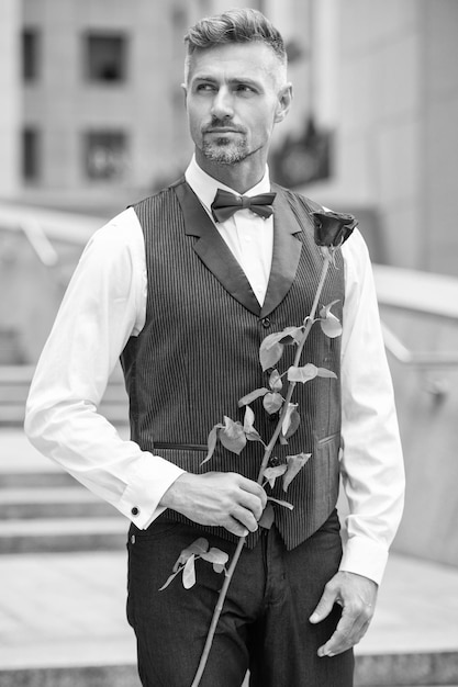 Liebestag-Konzept reifer Smoking Mann mit Liebe Rose Blume Geschenk für Liebestag