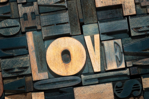 Liebeswort aus hölzernen Buchdruckblöcken im Hintergrund mit vielen Buchstaben