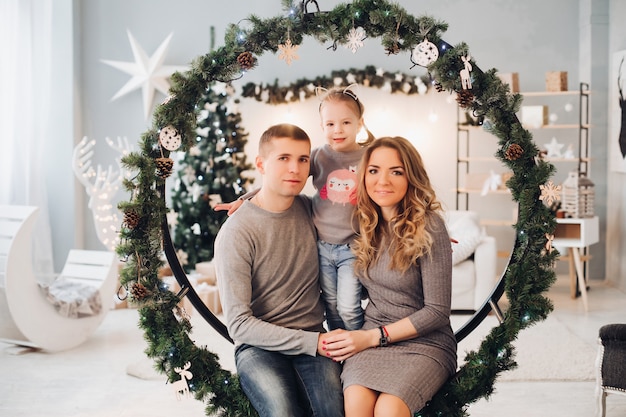 Liebevolle Familie, die auf Weihnachtsschwingen sich anschmiegt. Weihnachtsbaum.