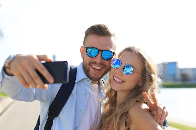 Liebevolle fröhliche glückliche Paare, die Selfie in der Stadt machen.