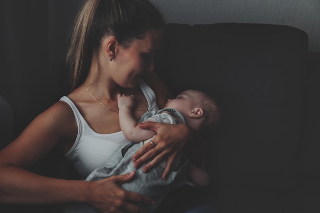 Liebevolle, glückliche Mutter, die zu Hause ein neugeborenes Baby trägt