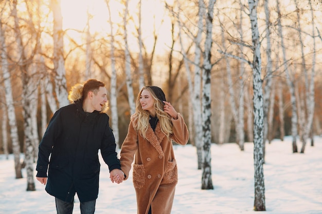 Liebevolle junge Paare, die im Winterwaldpark spazieren gehen und Spaß haben