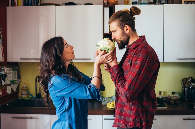 Liebevolle junge Paare, die zu Hause Gemüse in der Küche kochen