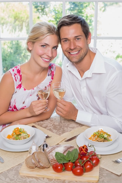 Liebevolle junge Paare mit Weingläsern am Speisetische