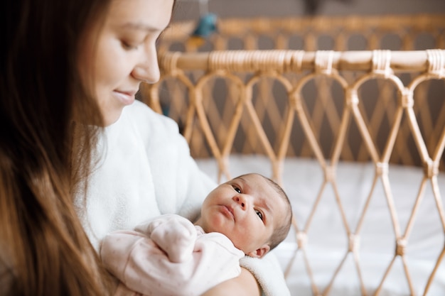 liebevolle Mama, die ihr neugeborenes Baby zu Hause pflegt Baby ruht im Bett