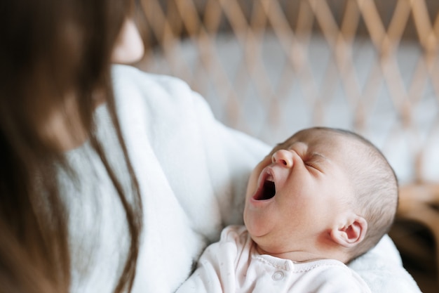 liebevolle Mama, die ihr neugeborenes Baby zu Hause pflegt