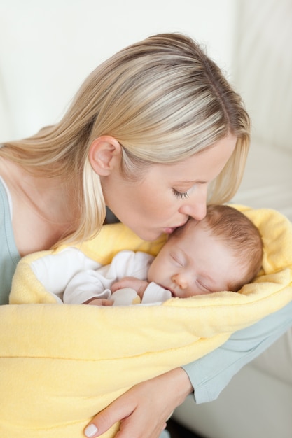 Liebevolle Mutter, die die Stirn ihres Babys küsst