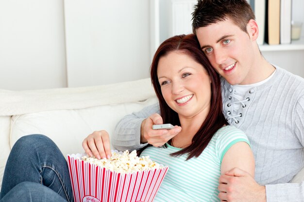 Liebevolle Paare, die auf dem Sofa fernsehend in liegen