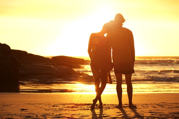 Liebevolle Paare, die den Strand betrachtet Sonnenuntergang bereitstehen