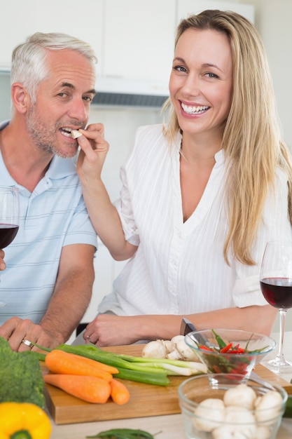 Liebevolle Paare, die zusammen Abendessen vorbereiten und Rotwein trinken