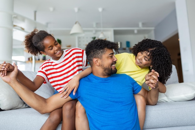 Liebevolle, vielfältige Eltern verbringen Zeit mit einer kleinen, entzückenden Tochter, haben Spaß zusammen im modernen Zuhause, lächeln, lachen aus nächster Nähe Fröhliches multiethnisches Familienkonzept